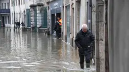 Seorang pria melintasi banjir di Ornans, Prancis timur (23/1). Akibat kondisi cuaca yang buruk, sejumlah sungai di Prancis meluap salah satu sungai Loue. (AFP Photo/Sebastien Bozon)