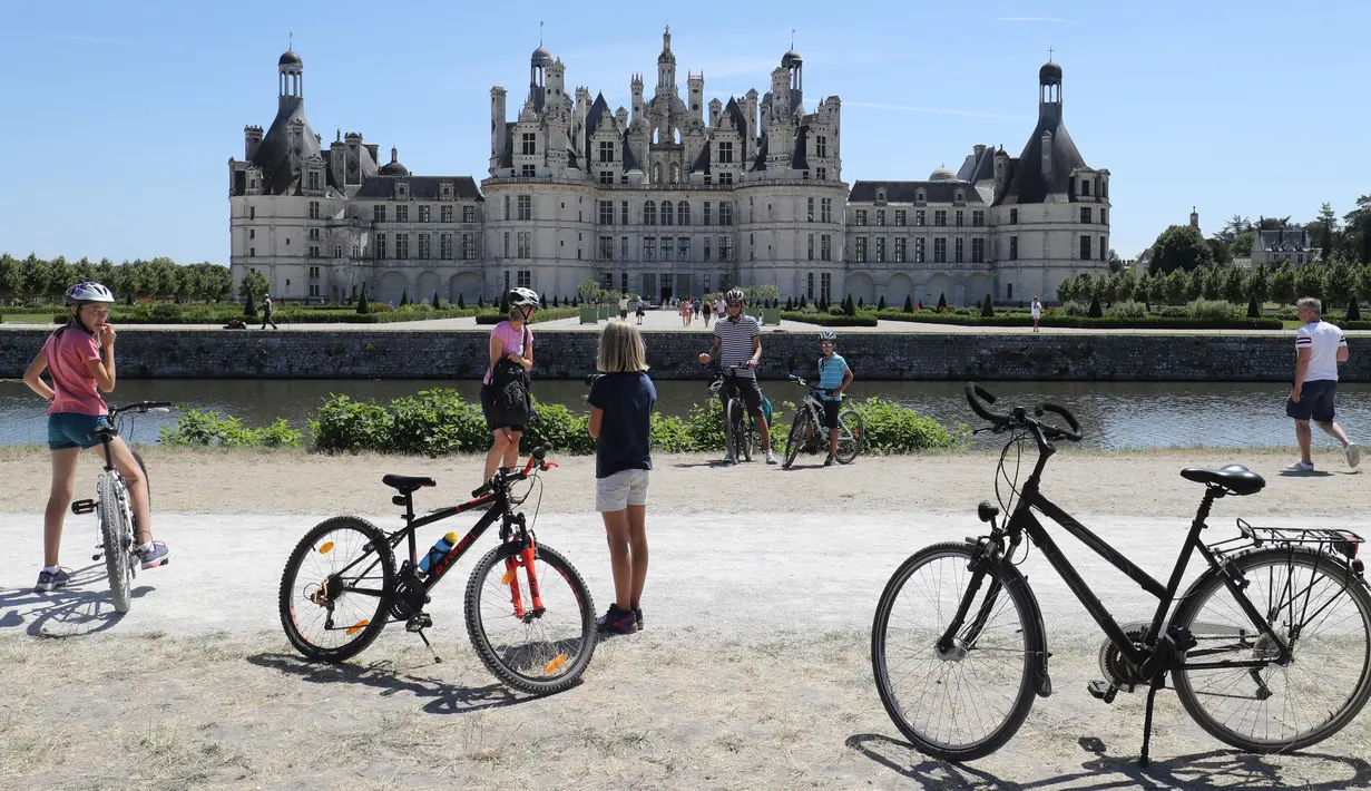 Pengendara sepeda mengunjungi Kastil Chambord, di Chambord, Prancis pada 22 Juli 2020. Bangunan bersejarah ini merupakan salah satu kastil terbesar di Prancis sekaligus lokasi nyata yang menginspirasi film pertama Beauty and The Beast, 26 tahun lalu. (Photo by Ludovic MARIN / AFP)