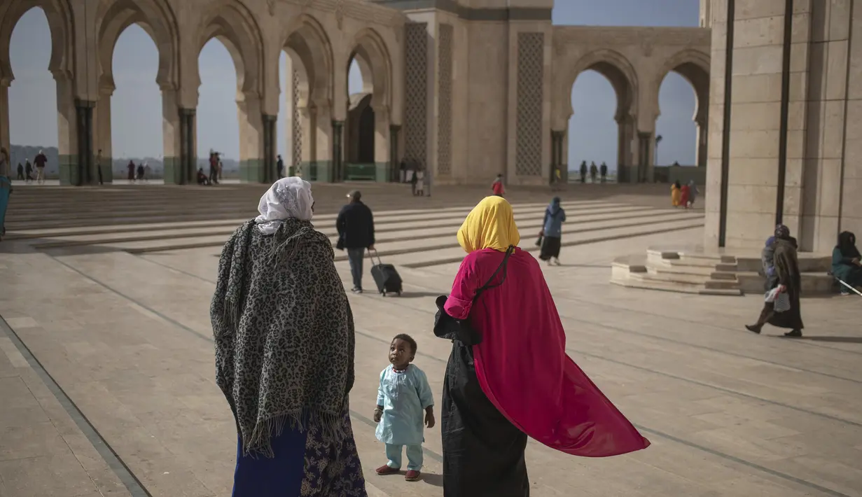 Sebuah keluarga Muslim berjalan setelah melaksanakan salat di luar masjid Hassan II, salah satu yang terbesar di Afrika, di Casablanca, Maroko (7/2/2020). Pelataran di masjid ini dapat mampu menampung 80 ribu jemaah. (AP Photo/Mosaab Elshamy)