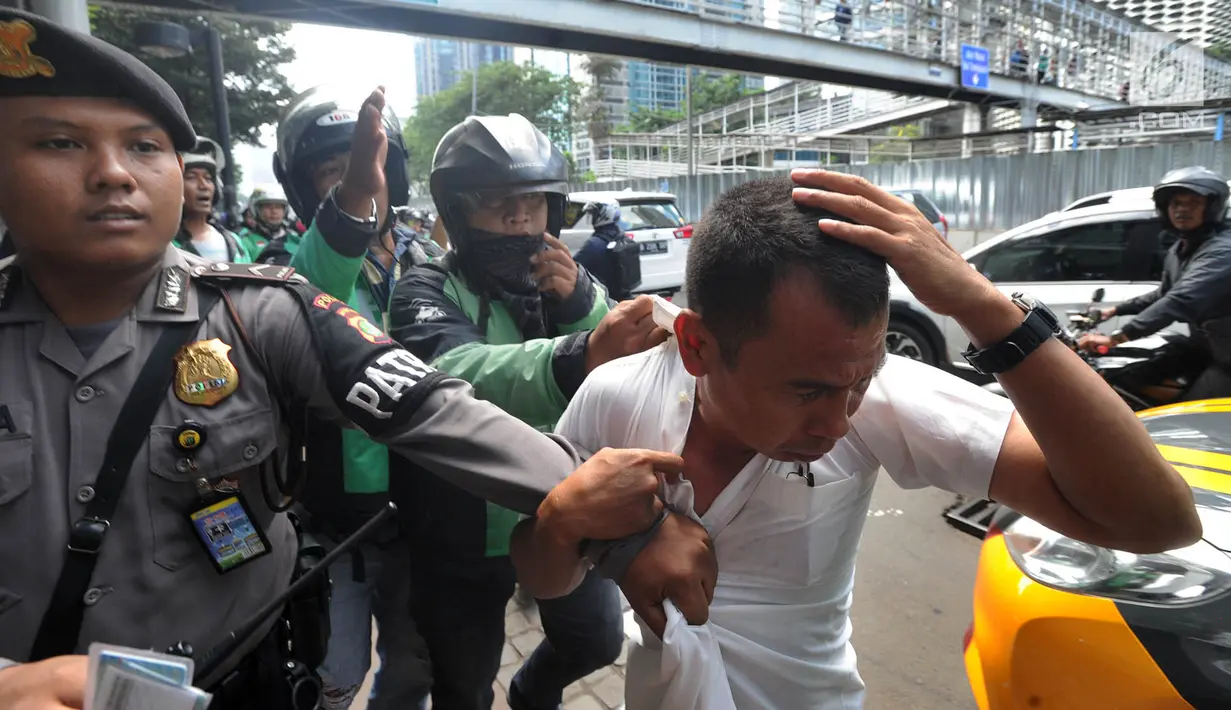 Terduga copet menutupi kepalanya dengan tangan saat akan diamankan menuju Mapolda Metro Jaya di Jalan Jenderal Sudirman, Jakarta (2/4). (Merdeka.com/Arie Basuki)