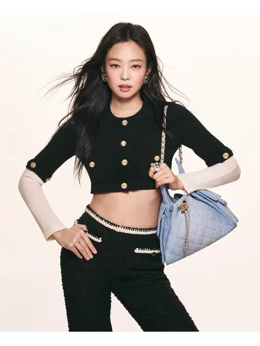 Jennie membawa Chanel 25 Handbag dalam warna biru denim quilted, memberikan sentuhan kasual namun tetap mewah. Warna biru lembut menciptakan kontras yang cantik dengan outfit hitamnya. Detail rantai emas khas CHANEL pada tas dan aksesori-nya semakin memperkuat aura mewah. [Dok/CHANEL].