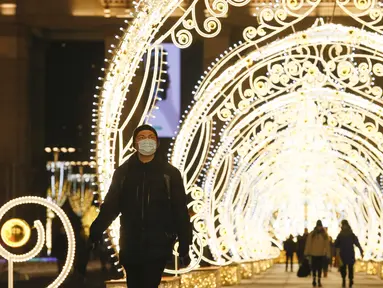 Seorang pria berjalan melewati lorong berhias lampu yang dipasang untuk menyambut libur Tahun Baru dan Natal Ortodoks di Moskow, Rusia, pada 29 Desember 2020. (Xinhua/Alexander Zemlianichenko Jr)