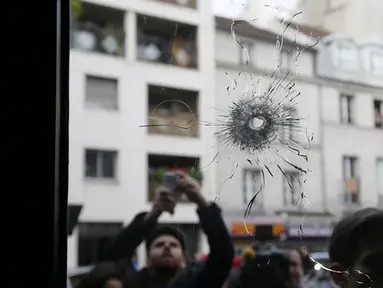 Wartawan tampak mengabadikan gambar kaca disebuah restoran dimana penembakan terjadi di Paris, Prancis, Sabtu (14/11/2015). Dikabarkan ratusan orang tewas dalam serangan ini. (REUTERS/Gonzalo Fuentes)