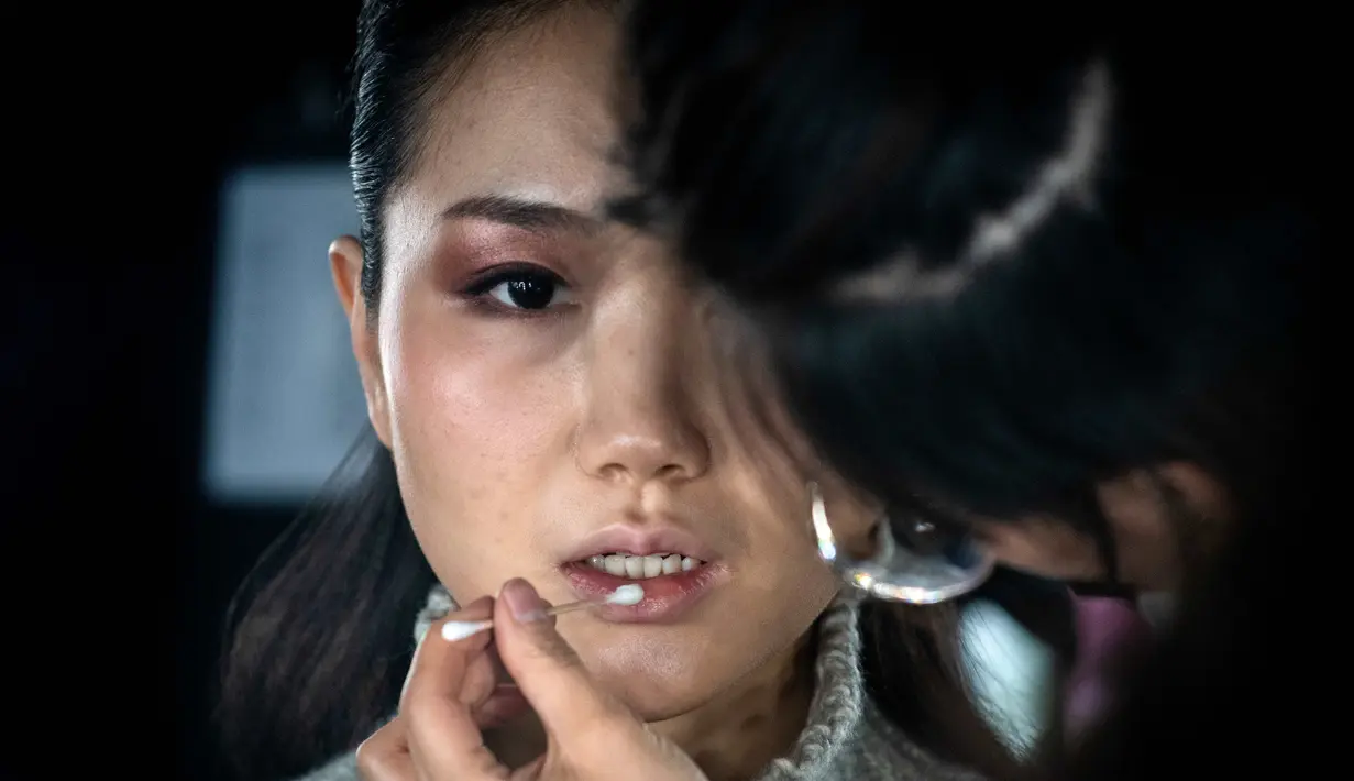 Model saat dirias di belakang panggung sebelum tampil membawakan koleksi Rabbit-Warm karya Zhuang Ganran selama China Fashion Week di Beijing (30/10). (AFP Photo/Nicolas Asfouri)