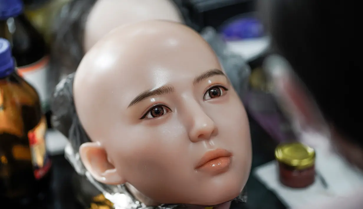 Seorang pekerja melukis wajah boneka seks di sebuah pabrik yang terletak di Dalian, China, Kamis (1/2). Pabrik boneka seks ini ingin menghubungkan orang-orang yang kesepian dan pensiunan dengan jenis pendamping baru. (AFP PHOTO/FRED DUFOUR)