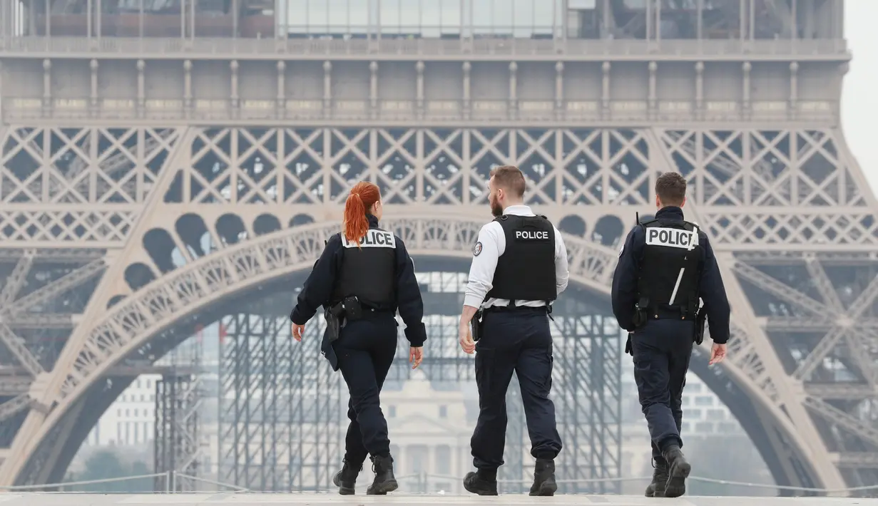 Polisi menyisir area lapangan Esplanade du Trocadero dekat Menara Eiffel saat lockdown di Paris, Prancis, Rabu (18/3/2020). Sampai Selasa (17/3/2020), Prancis memiliki 6.633 kasus virus corona COVID-19 dengan 148 kematian. (Ludovic MARIN/AFP)