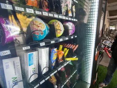 Mahasiswa melihat alat tes HIV yang dijual bersamaan dengan makanan ringan di dalam vending machine (mesin jual otomatis) di sebuah universitas di Chengdu, China, 27 November 2016. (REUTERS/Stringer)