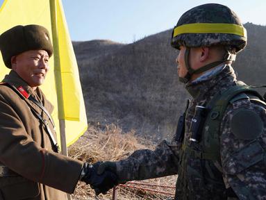 Tentara Korea Selatan berjabat tangan dengan tentara Korea Utara  sebelum melintasi Garis Demarkasi Militer di Cheorwon, Rabu (12/12). Mereka mulai memeriksa pembongkaran pos-pos penjaga di Zona Demiliterisasi. (HANDOUT/AFP/SOUTH KOREAN DEFENCE MINISTRY)