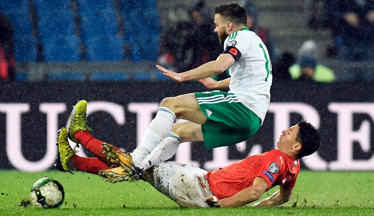 Bek Swiss, Fabian Schaer dan pemain Irlandia Utara, Stuart Dallas berebut bola pada leg kedua fase playoff Piala Dunia 2018 zona Eropa di St Jakob Park Stadium, Minggu (12/11). Swiss akhirnya lolos ke Piala Dunia 2018. (Jean-Christophe/Keystone via AP)