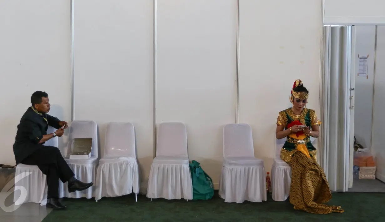Seorang petugas dan penari sedang memegang handphone dibalik panggung Pentas Budaya di Terminal 3, Bandara Soekarno Hatta, Tangerang, Banten, Senin (15/08). (Liputan6.com/Fery Pradolo).