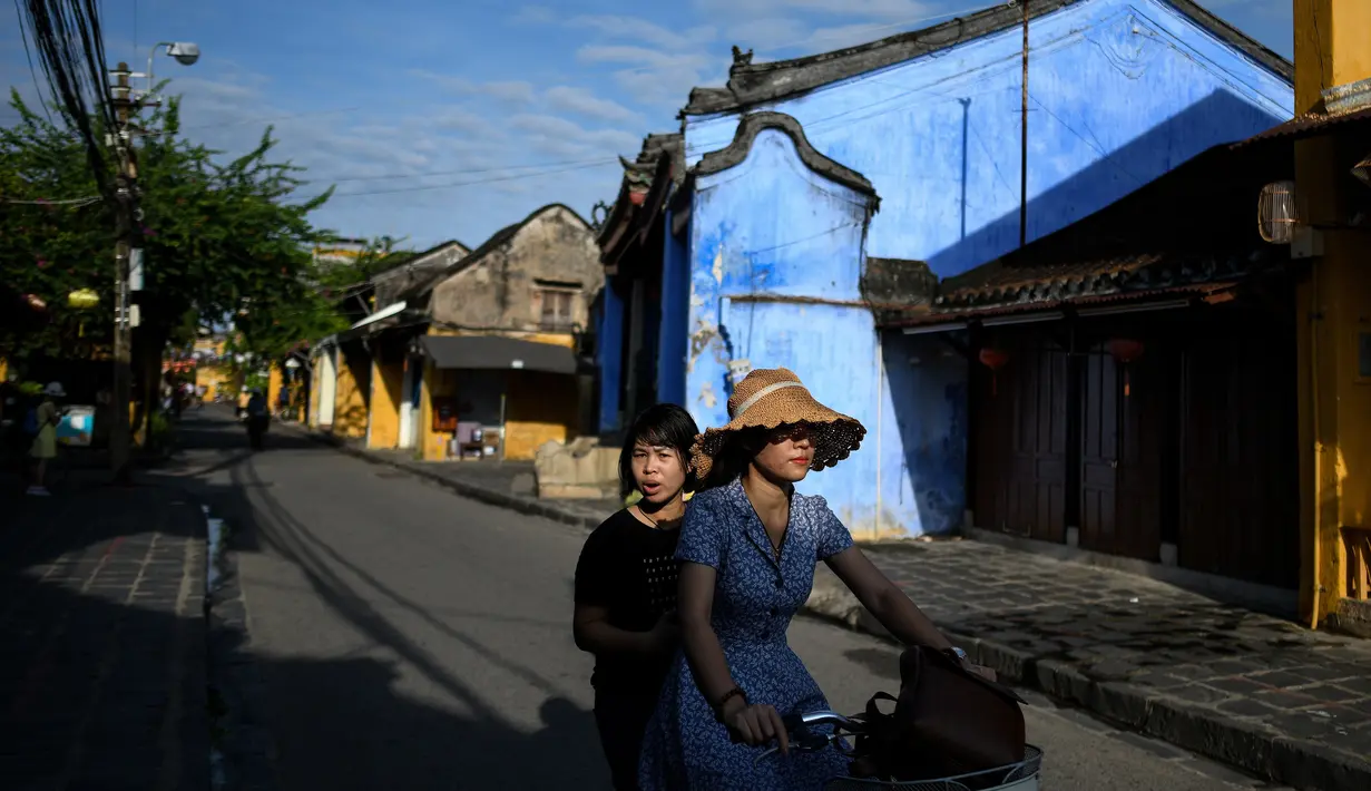 Gambar pada 14 September 2019 memperlihatkan para wisatawan mengendarai sepeda di kota tua Hoi An, Vietnam. Kota Tua Hoi An merupakan destinasi wisata yang cukup populer di Vietnam, didukung oleh statusnya sebagai salah satu Unesco World Heritage Site. (Manan VATSYAYANA/AFP)