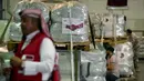 Karyawan Bulan Sabit Merah Qatar memegang spanduk berisi paket bantuan yang akan dikirim untuk wilayah yang terkena gempa di Turki, di Pangkalan Udara Al-Udeid di Qatar, Selasa, 7 Februari 2023. Gempa bumi dahsyat melanda Turki tenggara dan Suriah Senin dini hari, merobohkan ratusan bangunan serta menewaskan dan melukai ribuan orang. (AP Photo/Kamran Jebreili)