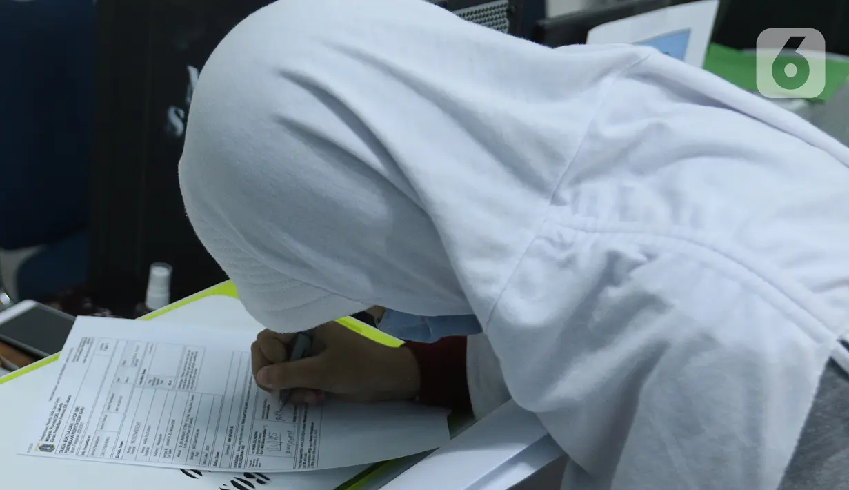 Calon siswa menandatangani bukti lapor diri usai pengurusan Penerimaan Peserta Didik Baru (PPDB) di SMPN 60 Jakarta, Rabu (17/6/2020). SMPN 60 Jakarta membuka penerimaan peserta didik baru melalui jalur afirmasi, anak tenaga medis yang terdampak COVID-19, dan inklusif. (Liputan6.com/Herman Zakharia)