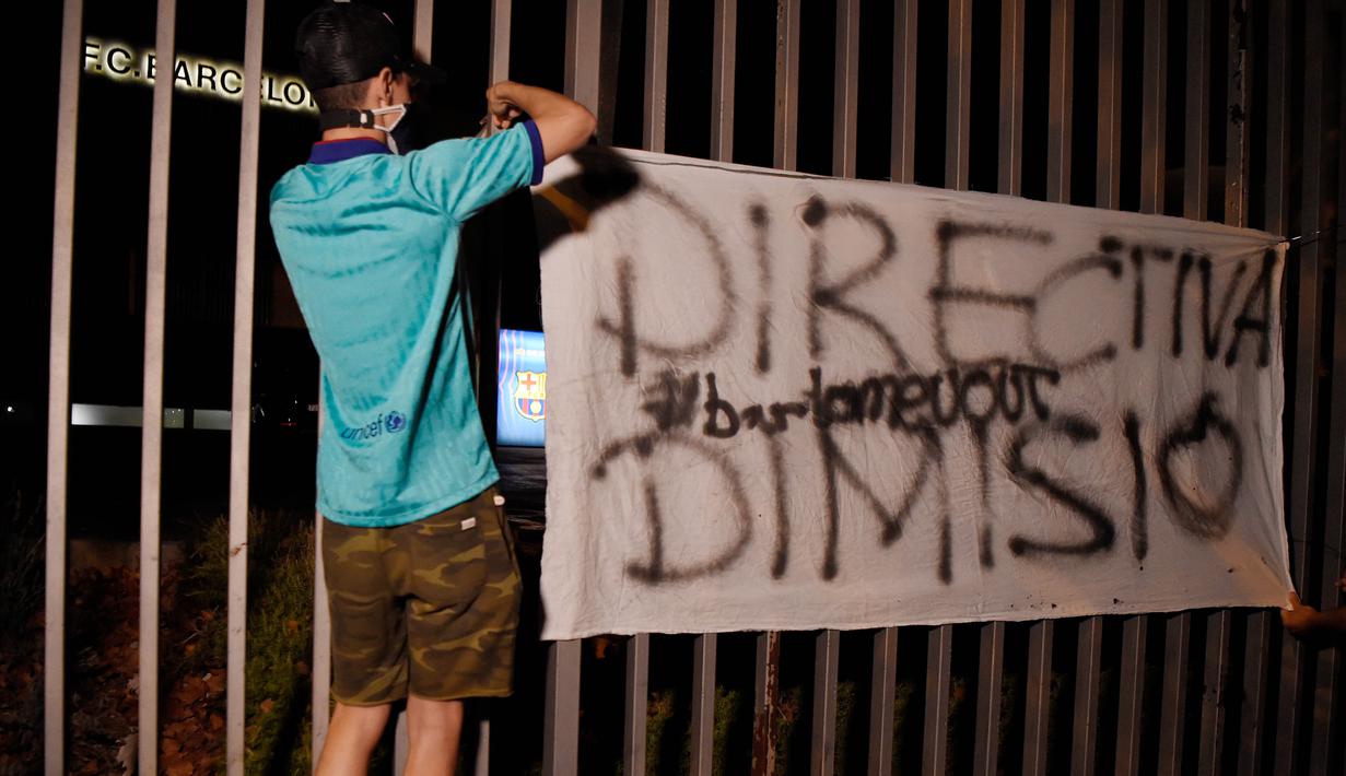 Suporter memasang spanduk saat melakukan protes di depan kantor Barcelona, Selasa (25/8/2020). Aksi tersebut merupakan respon fans atas kabar Lionel Messi yang akan meninggalkan Camp Nou pada musim panas ini. (AFP/Pau Barrena)