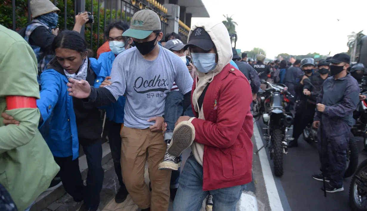 Massa gabungan dari berbagai elemen buruh dan organisasi mahasiswa menggotong rekannya saat unjuk rasa memperingati May Day di area Patung Kuda, Jakarta, Sabtu (1/5/2021). Polisi mengamankan sejumlah massa yang diduga mahasiswa dalam aksi unjuk rasa tersebut. (merdeka.com/Imam Buhori)