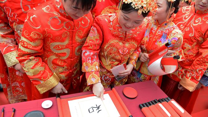 Mempelai membubuhkan sidik jari pada tulisan kaligrafi tradisional dalam pernikahan massal bergaya China di Changsha, Provinsi Hunan, China, 25 September 2020. Sebanyak 71 pasangan resmi menjadi suami-istri usai mengikuti upacara pernikahan tradisional dalam acara nikah massal. (Xinhua/Chen Zhenhai)