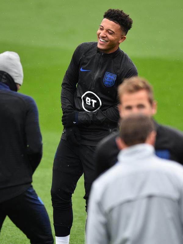 Gelandang Inggris, Jadon Sancho tertawa saat mengikuti sesi pelatihan tim  di Staplewood Campus di southampton, Inggris selatan (9/9/2019). Inggris akan bertanding melawan Kosovo pada grup A Kualifikasi Euro 2020 di Stadion Saint Mary. (AFP Photo/Glyn Kirk)