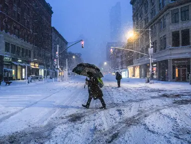 Para komuter berjalan melewati salju selama larangan perjalanan di seluruh kota New York pada Senin 23 Februari 2026. Badai musim dingin yang kuat melanda kawasan Atlantik Tengah dan Timur Laut Amerika Serikat (AS), membawa hujan salju lebat di Kota New York. (Ryan Murphy/Getty Images North America/Getty Images via AFP)