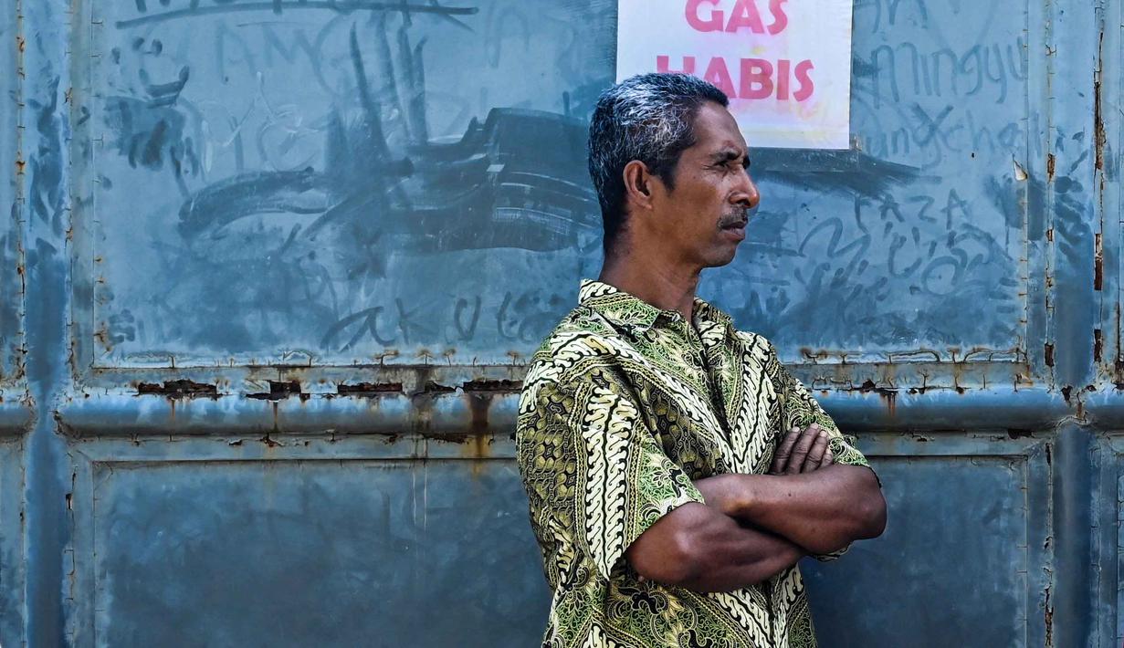 Kepastian kelancaran distribusi gas ini terkait upaya pemulihan kondisi daerah yang terdampak bencana banjir dan longsor di Sumatera. Tampak dalam foto, seorang pria berdiri di samping poster bertuliskan "Gas Habis" di sebuah SPBU setelah banjir bandang di Banda Aceh pada Rabu 17 Desember 2025. (CHAIDEER MAHYUDDIN/AFP)