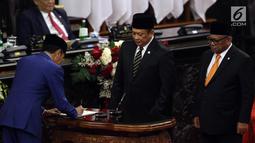 Presiden Joko Widodo menandatangani RUU tentang APBN TA 2020 beserta Nota Keuangan dan pendukungnya disaksikan Ketua DPR Bambang Soesatyo dan Ketua DPD Oesman Sapta Odang dalam Sidang Paripurna di Gedung DPR, Jakarta, Jumat (16/8/2019). (Liputan6.com/JohanTallo)