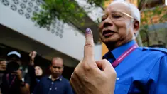 Perdana Menteri Malaysia, Najib Razak menunjukan jari yang telah diberi tinta usai memberikan hak suaranya di Pekan, Pahang, Rabu (9/5). Pemilu ini pertarungan antara PM Najib yang sudah berkuasa sejak 2009, melawan Mahathir Mohamad. (AP/Aaron Favila)