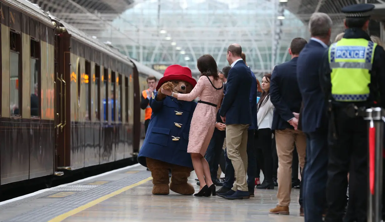 Kate Middleton asyik berdansa dengan seorang aktor yang mengenakan kostum Paddington di stasiun kereta Paddington, London, Senin (16/10). Ini merupakan kemunculan kedua Kate di publik sejak pengumuman kehamilan ketiganya. (Jonathan Brady/Pool via AP)