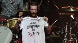Jesse Hughes, vokalis grup rock Eagles of Death Metal, memperlihatkan kaos ke hadapan penggemarnya sebelum memulai konser perdana mereka setelah serangan Paris pada November 2015 lalu, di gedung teater Olympia, Paris, Selasa (16/2). (AFP PHOTO/Joel SAGET)