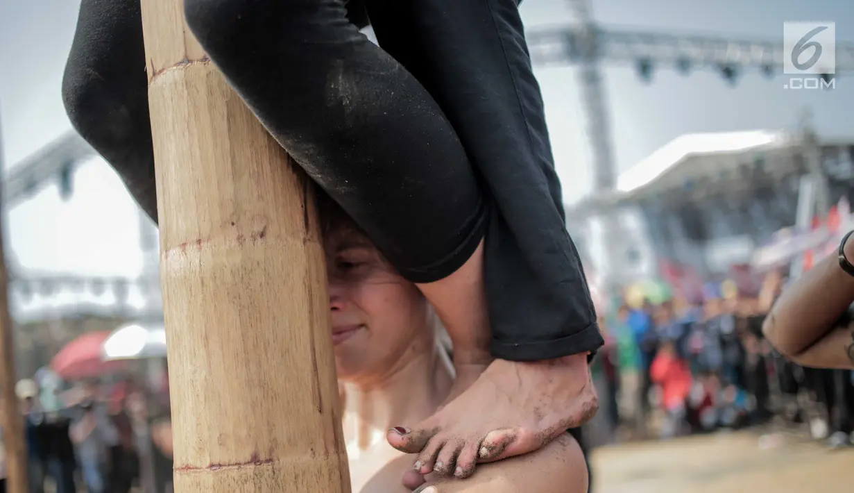 Ekspresi seorang warga negara asing mengikuti panjat pinang kolosal dalam rangka merayakan HUT ke-74 Kemerdekaan RI di Pantai Karnaval, Ancol, Jakarta, Senin (17/8/2019). Sebanyak 174 batang pinang dengan beragam hadiah disediakan dalam lomba yang diikuti ratusan warga itu. (Liputan6.com/Faizal Fana