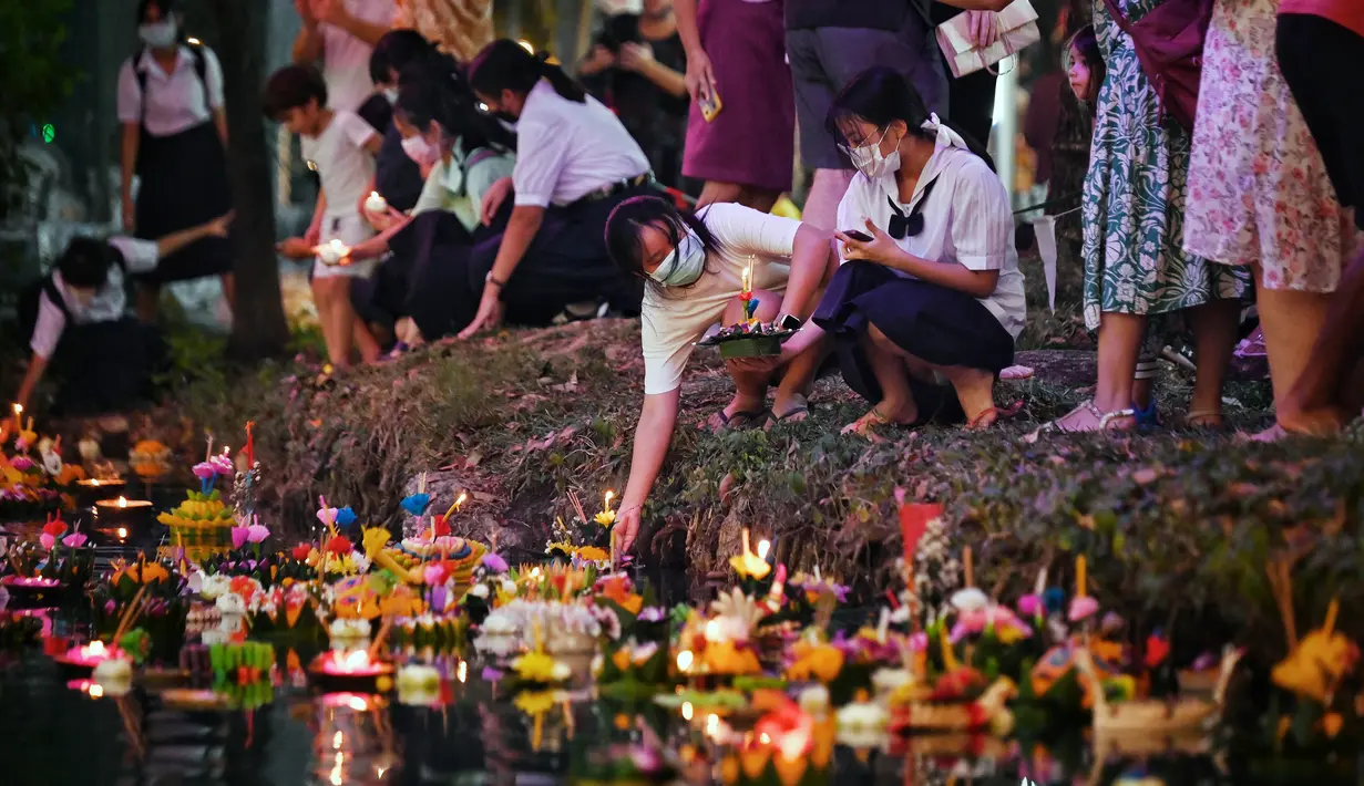 Orang-orang melepaskan lampion mengambang di kolam selama festival Loy Krathong di Bangkok (8/11/2022). Penghormatan tersebut dilakukan dengan cara melepaskan teratai yang dihiasi dengan lilin, dupa dan bunga ke air. (AFP/Lillian Suwanrumpha)