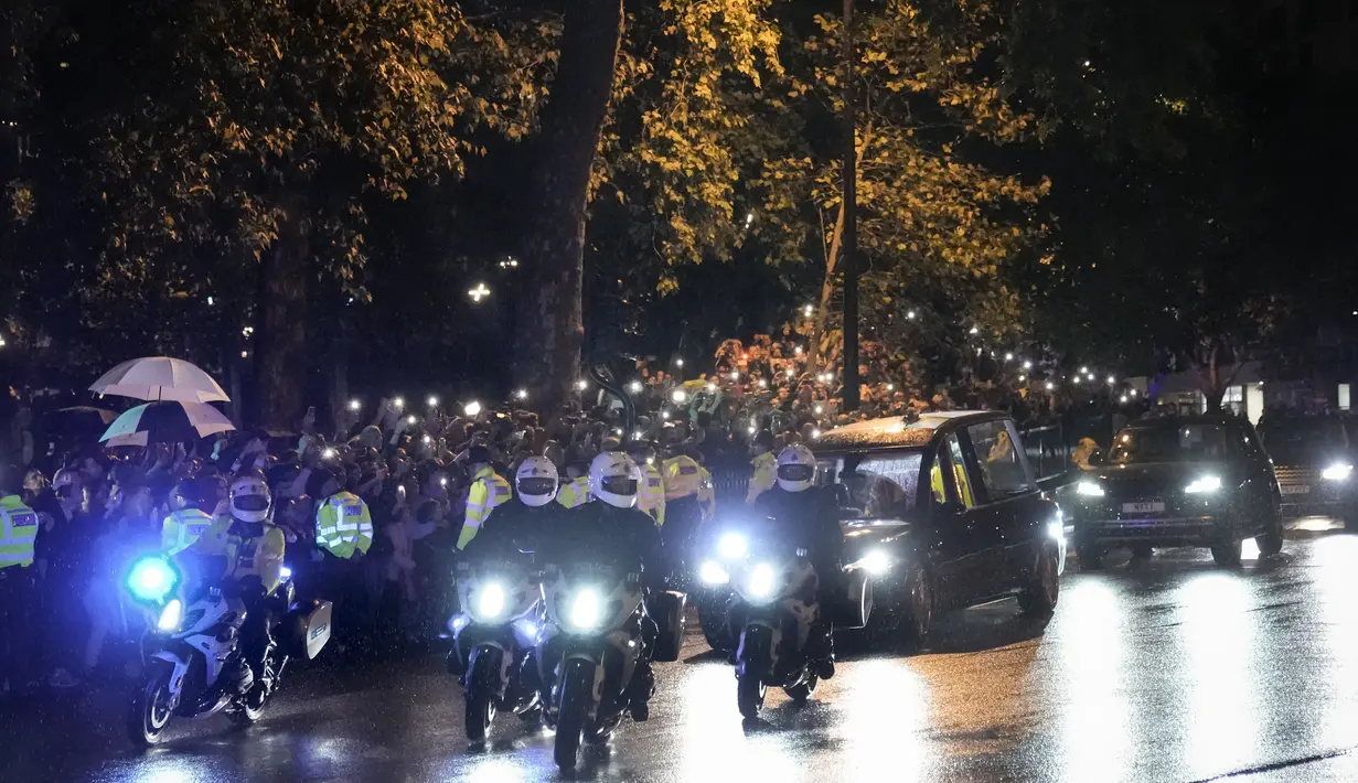 Mobil jenazah  yang membawa peti mati Ratu Elizabeth II menuju ke Istana Buckingham di London, Selasa (13/9/2022). Ratu Elizabeth II, raja terlama yang memerintah Inggris dan batu stabilitas di sebagian besar abad yang bergejolak, meninggal Kamis 8 September 2022, setelah 70 tahun bertahta, pada usia 96 tahun. (AP Photo/Andreea Alexandru)