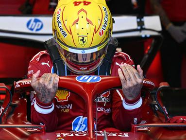 Pembalap Ferrari, Lewis Hamilton masuk ke kokpit mobilnya dalam sesi latihan bebas Formula 1 GP Australia 2025 di Sirkuit Albert Park, Melbourne, Australia pada Jumat (14/03/2025). (AFP/Saeed Khan)