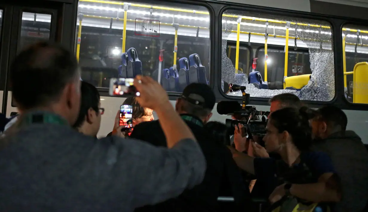 Seorang pria mengambil gambar kaca jendela bus pengangkut para jurnalis di Olimpiade Rio 2016 yang pecah ketika dalam perjalanan menuju pusat media centre di Barra da Tijuca, Selasa (9/8). Tak ada korban jiwa dalam insiden itu. (REUTERS/Adrees Latif)