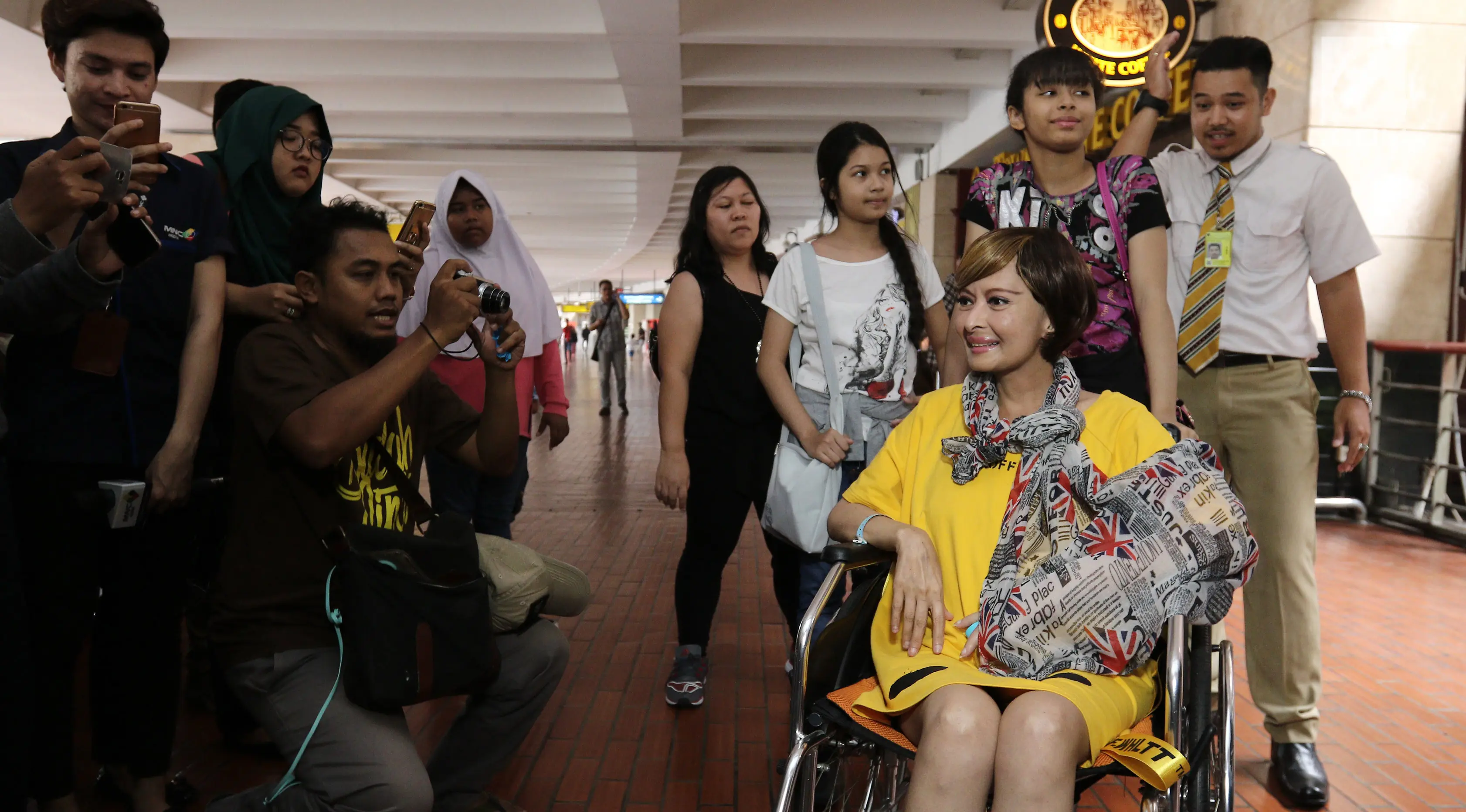 Sejumlah orang memotret Yana Zein saat tiba di bandara Bandara Soekarno Hatta, Tangerang, Minggu (28/5). Yana Zein kembali ke Tanah Air, setelah menjalani pengobatan kanker di Tiongkok. (Liputan6.com/Herman Zakharia)
