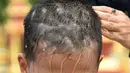 Anggota keluarga mencukur rambut seorang anak, yang diselamatkan dari gua di Thailand, pada upacara pentahbisan di Kuil Wat Phra That Doi Wao, Selasa (24/7). Sebanyak 11 remaja menjalani ritual menjadi biksu. (Panumas Sanguanwong/THAI NEWS PIX/AFP)