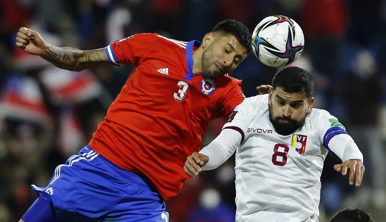 Pemain Chile Guillermo Maripan (kiri) dan pemain Venezuela Tomas Rincon melakukan sundulan pada pertandingan kualifikasi Piala Dunia 2022 di Stadion San Carlos de Apoquindo, Santiago, Chile, Kamis (14/10/2021). Chile menang 3-0. (Marcelo Hernandez/Pool via AP)