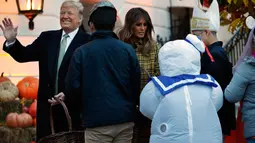 Presiden AS Donald Trump melambaikan tangan ketika dirinya dan Ibu Negara Melania Trump memberikan permen kepada anak-anak selama yang hadir acara trick-or-treat pada perayaan Halloween di Gedung Putih, Washington, Minggu (28/10). (AP/Jacquelyn Martin)