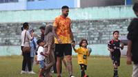 gelandang Arema FC, Julian Guevara membawa dua anaknya ke lapangan usai pertandingan ujicoba di Stadion Gajayana. (Bola.com/Iwan Setiawan)