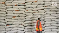 Pekerja berjalan di dekat susunan karung berisi beras di Gudang Bulog Divisi Regional DKI Jakarta, Kelapa Gading, Kamis (18/3/2021). Adapun dari total pengadaan sebanyak 1.785.450 ton beras, tersisa 275.811 ton beras belum tersalurkan. (merdeka.com/Iqbal S Nugroho)