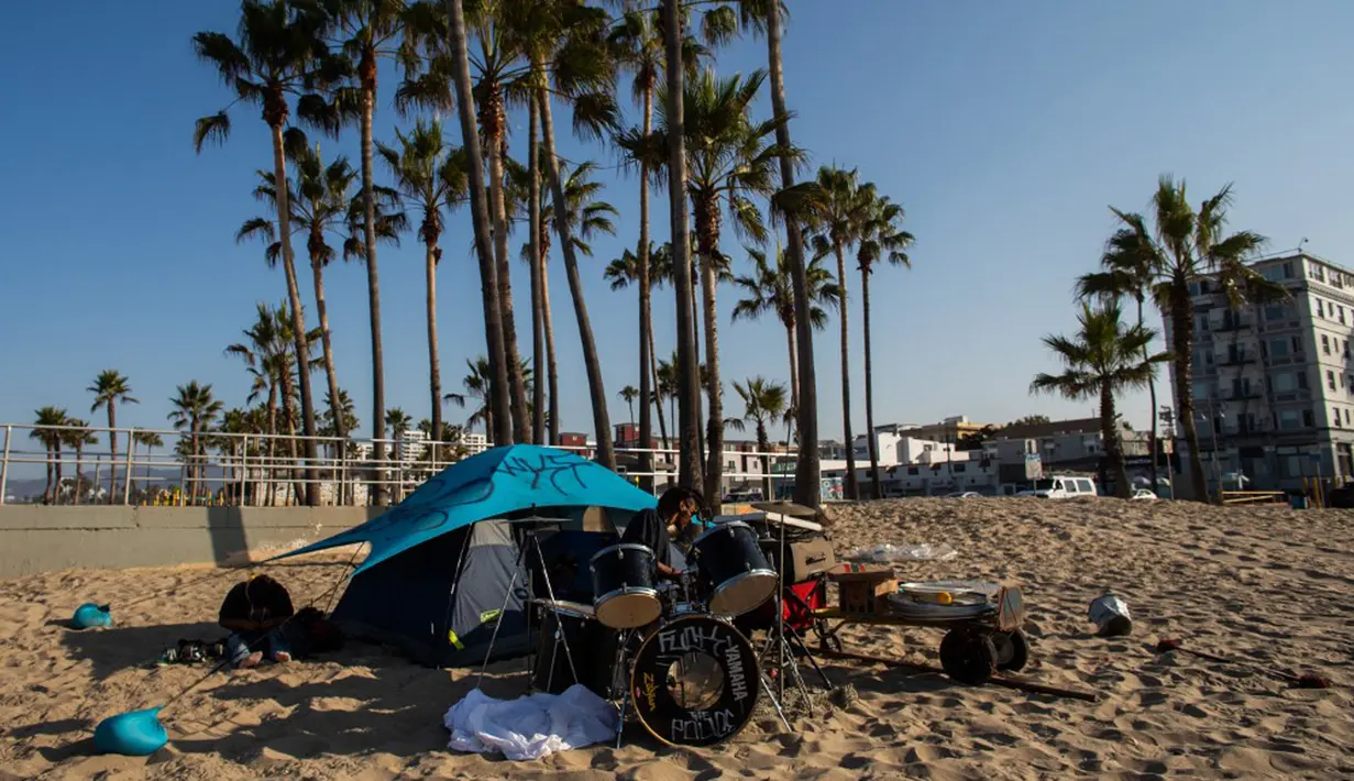 Seorang pria tunawisma bermain drum pada pagi hari di Venesia, California, Amerika Serikat, 12 Agustus 2021. (Apu GOMES/AFP)