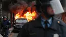 Aparat kepolisian berjaga di dekat sebuah limusin yang dibakar dalam aksi protes warga saat berlangsungnya upacara pelantikan Donald Trump menjadi Presiden Amerika Serikat yang ke-45 di Washington, DC, AS, (20/1). (AP Photo/John Minchillo)