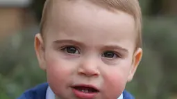 Foto yang dirilis oleh Kensington Palace pada 22 April 2019 memperlihatkan Pangeran Louis di rumahnya di Norfolk, Anmer Hall. Mengenakan baju hangat, Pangeran Louis memamerkan dua gigi bawah di bagian depan mulutnya sambil bermain di rerumputan. (THE DUCHESS OF CAMBRIDGE/KENSINGTON PALACE/AFP)