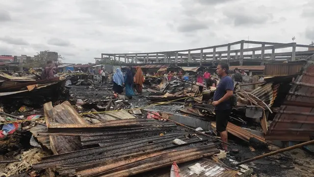 Salah satu pedagang di Pasar Cik Puan Pekanbaru melihat bekas kiosnya yang terbakar.