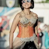 Ia pun tampil dengan riasan minimalis hanya terlihat lipstik orangenya. Dan bergaya dengan rambut pendek hitamnya. Credit: Instagram  (@popsovia)