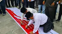 Tokoh Nahdatul Ulama Riau, Rusli Ahmad (kiri) menandatangani penolakan Rizieq Shihab dalam aksi damai di Pekanbaru. (Liputan6.com/M Syukur)