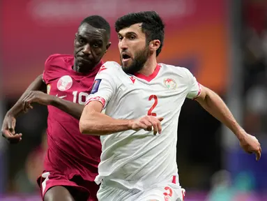 Pemain Tajikistan Zoir Dzhuraboev (kanan) dan pemain Qatar Almoez Ali berlari mengejar bola pada pertandingan sepak bola Grup A Piala Asia di Stadion Al Bayt, Al Khor, Qatar, Rabu (17/1/2024). (AP Photo/Aijaz Rahi)