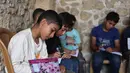Anak-anak Palestina mencatat saat menghadiri kelas di sekolah bersejarah "Al-Kamaliya al-Othmanya" di Kota Tua Gaza yang menjadi bagian dari inisiatif sukarelawan yang diorganisir oleh para guru pengungsi, di Kota Gaza pada 2 November 2025. Saat ini, diperkirakan sekitar satu dari enam anak usia sekolah telah kembali ke kelas untuk kembali mengikuti kegiatan belajar.  (Omar AL-QATTAA/AFP)