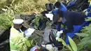 Petugas kepolisian Kenya mengumpulkan barang-barang dari puing-puing bus yang jatuh ke jembatan Nithi pada hari Minggu, di Kabupaten Tharaka Nithi, Kenya, Senin (25/7/2022). Saat kejadian, bus milik perusahaan Modern Coast itu tengah melakukan perjalanan dari Meru ke Kota Mombasa. (AP Photo/Dennis Dibondo)