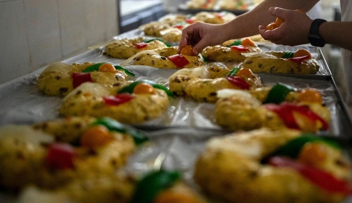 Seorang tukang roti membuat Bolo Rei atau Kue Raja di toko roti Padaria da Ne, Amadora, Portugal, 16 Desember 2022. Selain disebut sebagai fruit cake-nya Portugal, Bolo Rei juga disebut sebagai Kue Raja. (CARLOS COSTA/AFP)