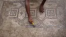 Petani Palestina Salman al-Nabahin membersihkan lantai mosaik era Bizantium yang ditemukan di Bureij, Jalur Gaza, Palestina, 18 September 2022. Nabahin mengatakan kepada kantor berita Reuters bahwa dia menyadari bahwa mosaik itu milik era Bizantium setelah mencari di internet. (MOHAMMED ABED/AFP)