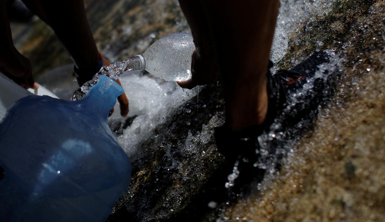 Warga mengumpulkan air yang keluar melalui saluran pembuangan air limbah yang mengalir ke Sungai Guaire di Caracas, 11 Maret 2019. Pemadaman listrik selama berhari-hari di Venezuela berdampak terhadap krisis air. (REUTERS/Carlos Garcia Rawlins)